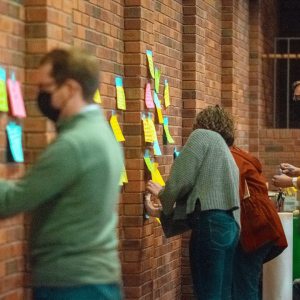 Young Adults posting their consolations written on post it notes on the wall of the chapel. 